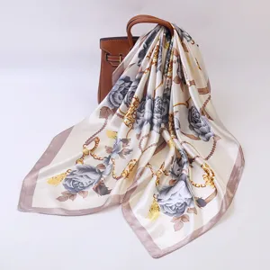 Luxury silk square scarf detail with elegant grey rose and gold chain print design.