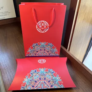 Red silk scarf gift box packaging set with elegant ethnic mandala patterns and paper bags.