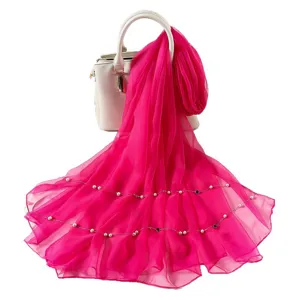 Stunning hot pink chiffon scarf with pearl chains draped on handbag for summer fashion.