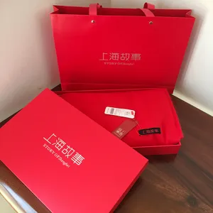 Red silk scarf gift set box detail view, elegant packaging bag and premium fabric presentation.