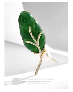 Detailed close-up shot of exquisite gold-plated leaf brooch with sparkling zirconia and pearl decor.