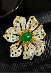 Detail shot of a luxurious gold-plated flower brooch featuring sparkling zirconia and green agate.