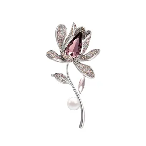 Elegant silver-tone crystal orchid brooch pin with purple stone and pearl decor.