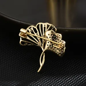Elegant double ginkgo leaf brooch featuring emerald zirconia crystals, chic suit accessory for women.