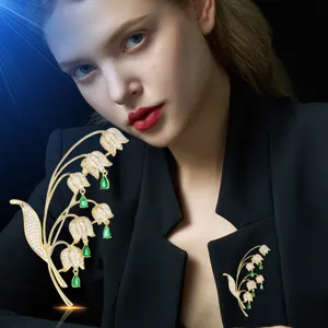 Elegante spilla a forma di mughetto con cristalli scintillanti e pietre verdi.