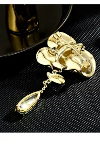 Detailed back view of golden lotus brooch with sparkling crystal teardrop pendant accessory.