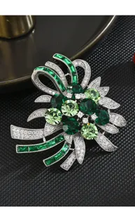 Close-up detail of luxury green crystal rhinestone ribbon brooch with sparkling paved stones.