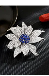 Close-up of elegant flower brooch featuring sparkling crystals and blue center stones details.