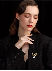 Exquisite pearl bow brooch detail shot, elegant gold metal accessory for clothing.