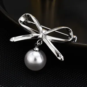 Elegant silver bow brooch featuring a hanging pearl pendant for women fashion accessories.