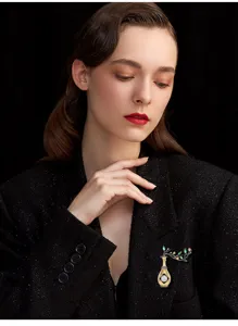 Elegant retro vase pearl brooch detail, featuring dual-color gold and delicate gemstone leaves.