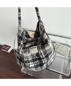 Detailed view of a cozy black and white plaid fuzzy shoulder tote bag hanging on a silver rack