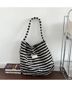Close-up detail of retro black and white striped plush tote bag in a cozy home setting
