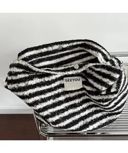 Macro view of black and white striped plush tote bag with SEEYOU label and snap button
