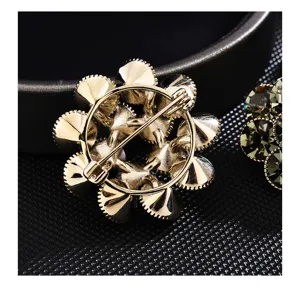 Vue détaillée du dos de broche fleur dorée, incrustation cristaux, mécanisme de fermeture sûr