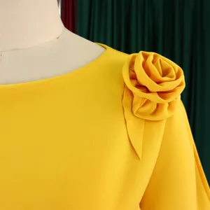 Primo piano del dettaglio della spalla di un abito giallo con fiore in tessuto 3D.