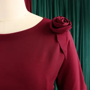 Primo piano della spalla di un abito rosso vino con rosa in tessuto.