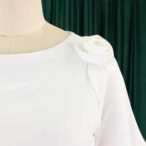 Dettaglio di un abito bianco elegante con decorazione floreale 3D sulla spalla