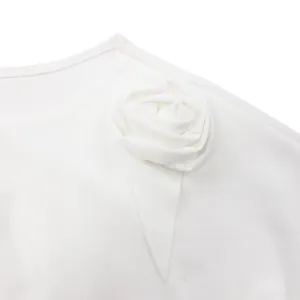 Dettaglio ravvicinato di un abito bianco elegante con una decorazione a rosa 3D