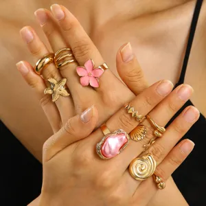 Dettaglio ravvicinato di set anelli vintage dorati con fiori rosa e perle barocche