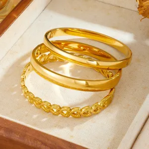 Detailed close-up of gold-plated titanium steel bangles featuring plain and hollow heart designs.