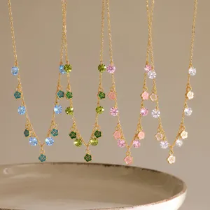 Close-up detail of delicate gold-plated chain necklace with colorful crystal stones and enamel flowers.