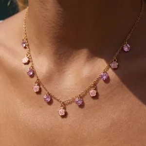 Chic gold-tone chain necklace featuring charming pink flower charms and sparkling purple crystals.