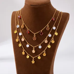 Detail view of multi-layer gold necklace featuring delicate rose charms and sparkling crystal pendants.