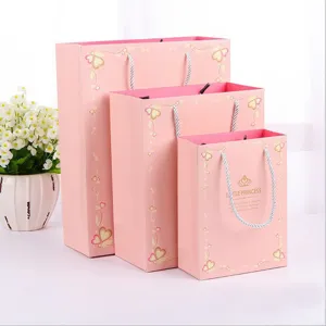 Roze papieren geschenkzak detailweergave, decoratief hartpatroon en stevige touwhandvatten.