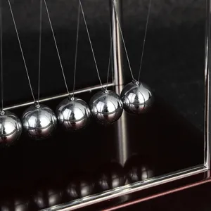 Primo piano dettagliato delle sfere metalliche del pendolo di Newton e arredamento da scrivania.