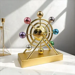 Scultura cinetica dorata perpetuum mobile con sfere colorate per moderna decorazione da tavola.