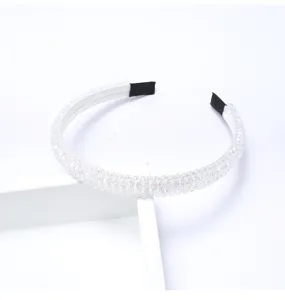Gros plan sur le serre-tête en perles de cristal transparentes, accessoire de coiffure fin.
