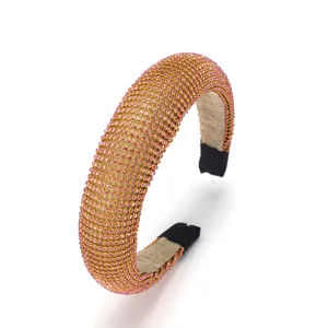 Gros plan du serre-tête rembourré en strass avec cristaux roses étincelants et base dorée.