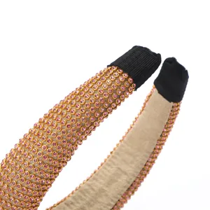 Gros plan d'un large headband en strass, cristaux roses scintillants sur une monture dorée.