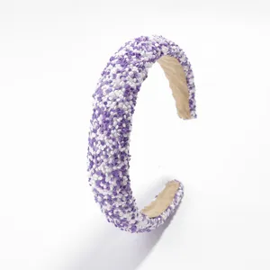 Detalle en primer plano de una diadema acolchada ancha con lentejuelas moradas y blancas.