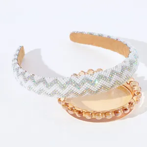 Dettaglio di un cerchietto per capelli con perle e strass a chevron su vassoio.
