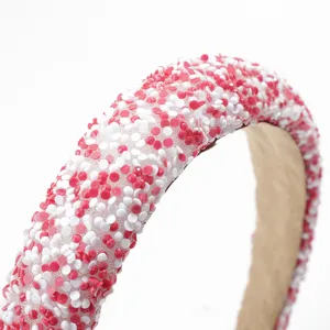 Detalle de la diadema ancha y acolchada de pedrería con cuentas brillantes rosas y blancas.