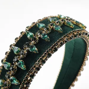 Close-up detail of dark green velvet headband with sparkling green crystals and gold setting.