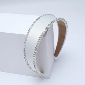 Vue détaillée d'un serre-tête large en satin blanc orné de doubles strass scintillants.