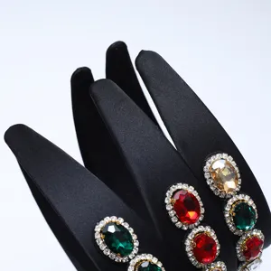 Dettaglio ravvicinato del cerchietto in raso nero con strass e pietre preziose colorate.