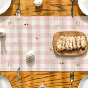 Gros plan du chemin de table en lin à carreaux roses avec un délicat imprimé floral.