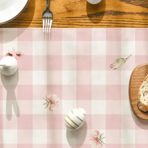 Gros plan d'un chemin de table à carreaux roses avec motif floral et déco de Pâques.