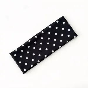 Dettaglio di una fascia sportiva elastica e alla moda a pois neri e bianchi per capelli.
