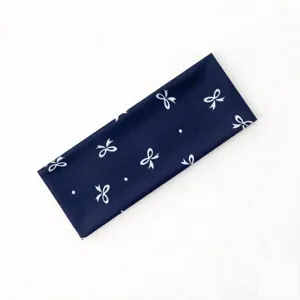 Dettaglio della fascia per capelli blu scuro larga con graziosi fiocchi e pois bianchi.