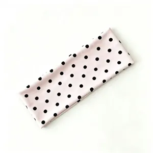Primo piano dettaglio di una simpatica fascia sportiva a pois rosa e neri da donna, elastica.