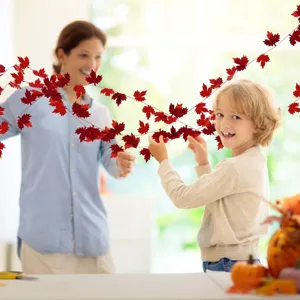 Detail shot of red maple leaf garland hanging for Thanksgiving party decoration, autumn style.