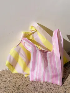 Close-up detail of pink and yellow striped foldable shopping bags, portable waterproof eco tote.