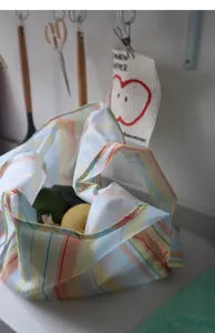 Detailed view of striped foldable shopping bag with fresh produce, lightweight waterproof fabric.