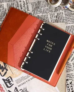 Minimalist loose-leaf retro leather planner notebook with black pages and elegant gold text.