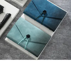 Detailed view of leather travel notebooks with elastic band closure in blue and green.